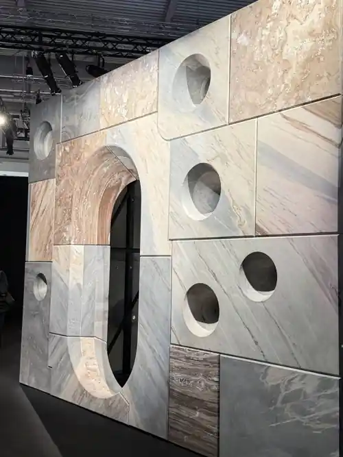 Marble and travertine wall with round cutouts made on a CNC